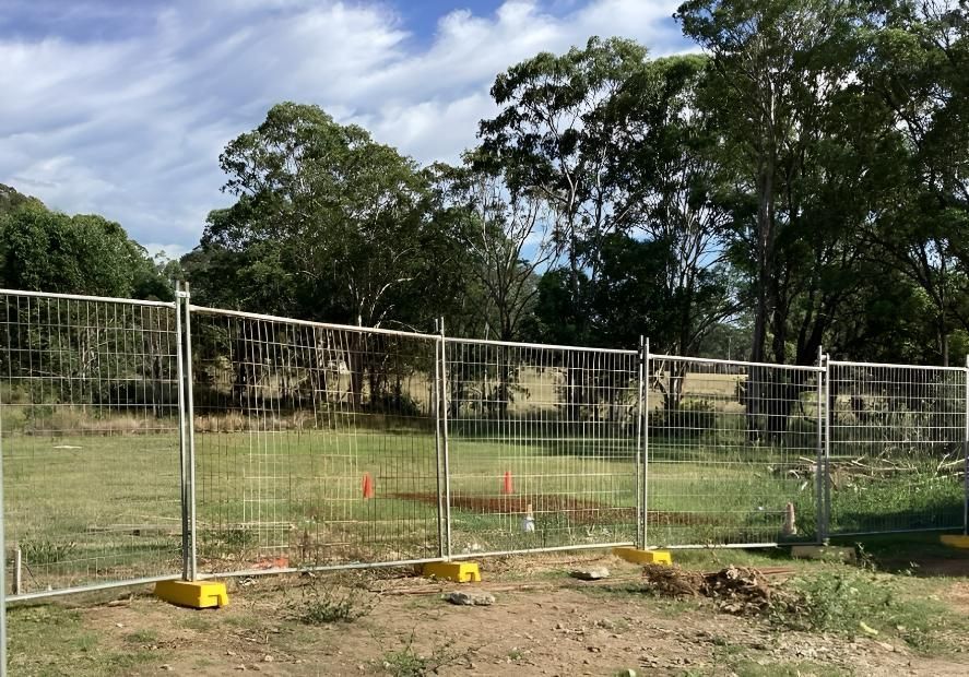 A Fence Is Surrounding a Field with Trees in The Background — Site Safety NSW in Lake Macquarie, NSW