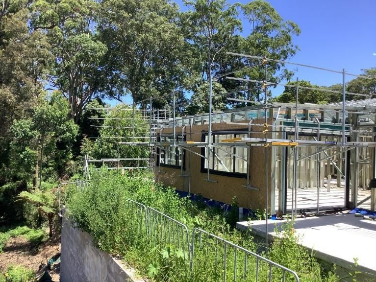 A Building Under Construction Is Surrounded by Trees and Scaffolding — Site Safety NSW in Sandgate, NSW
