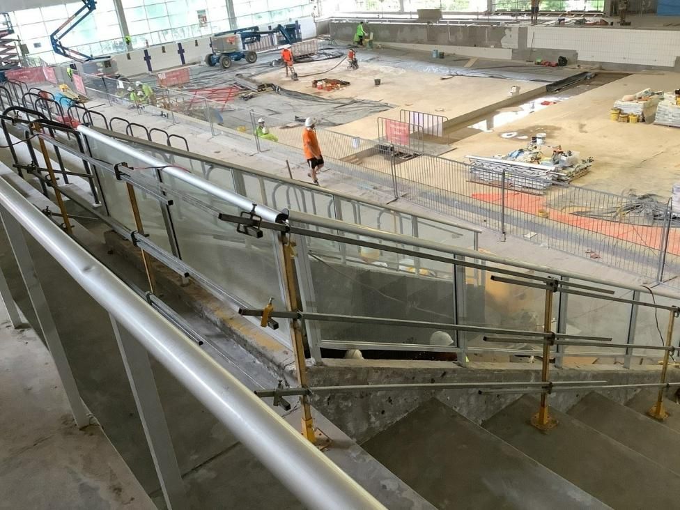A Man Is Walking Down a Staircase in A Building Under Construction — Site Safety NSW in Sandgate, NSW