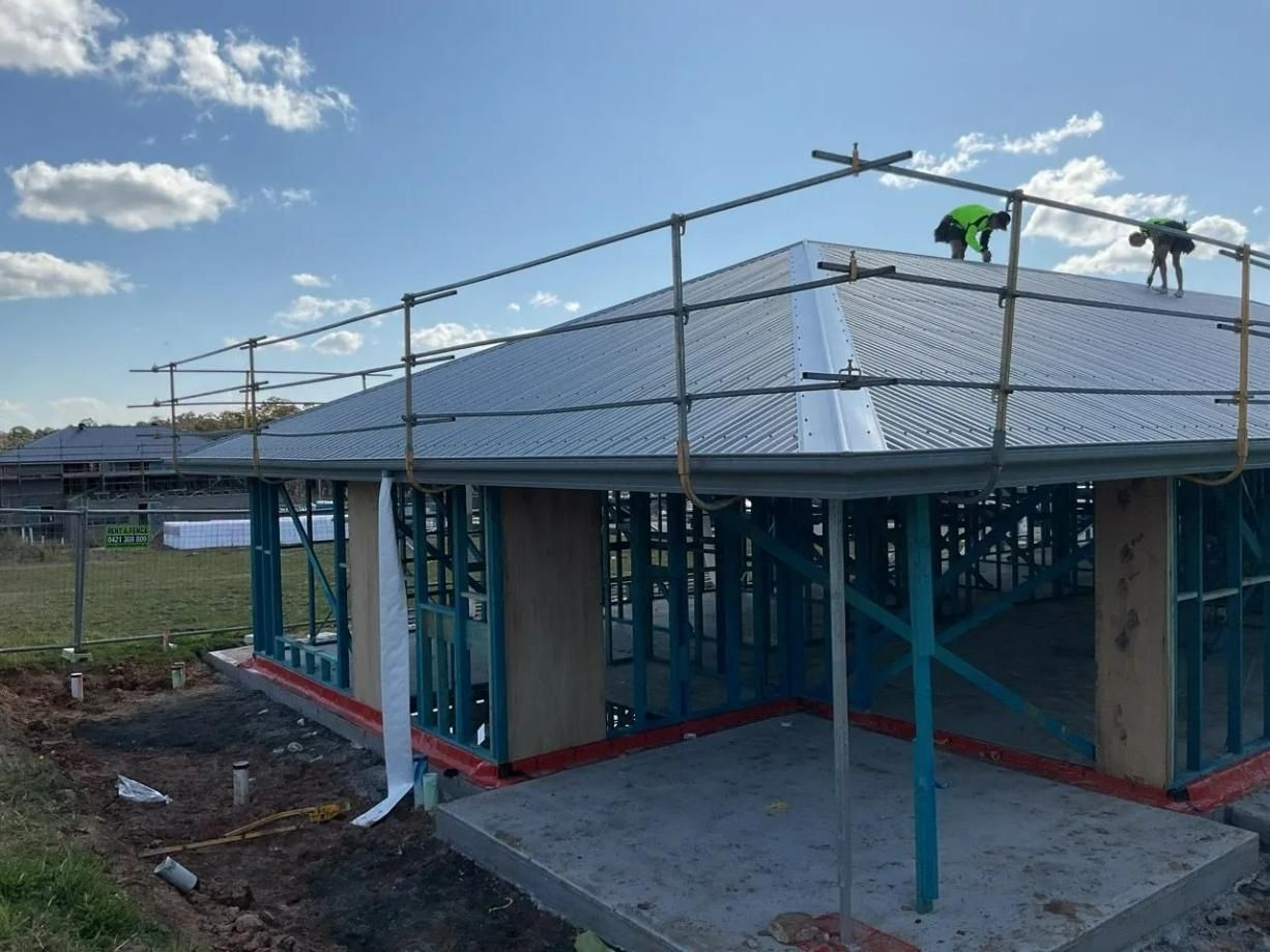 A Man Is Working on The Roof of A House Under Construction — Site Safety NSW in Sandgate, NSW