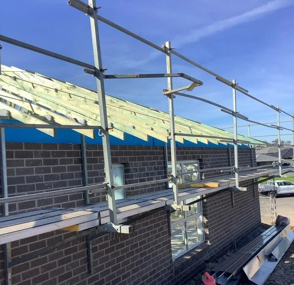 A Brick Building Under Construction with Scaffolding Around It — Site Safety NSW in Mid North Coast, NSW