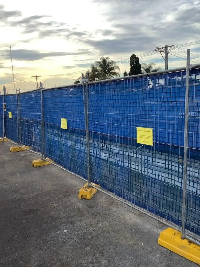 A Blue Fence with Yellow Signs on It Is Sitting on The Side of The Road — Site Safety NSW in Sandgate, NSW
