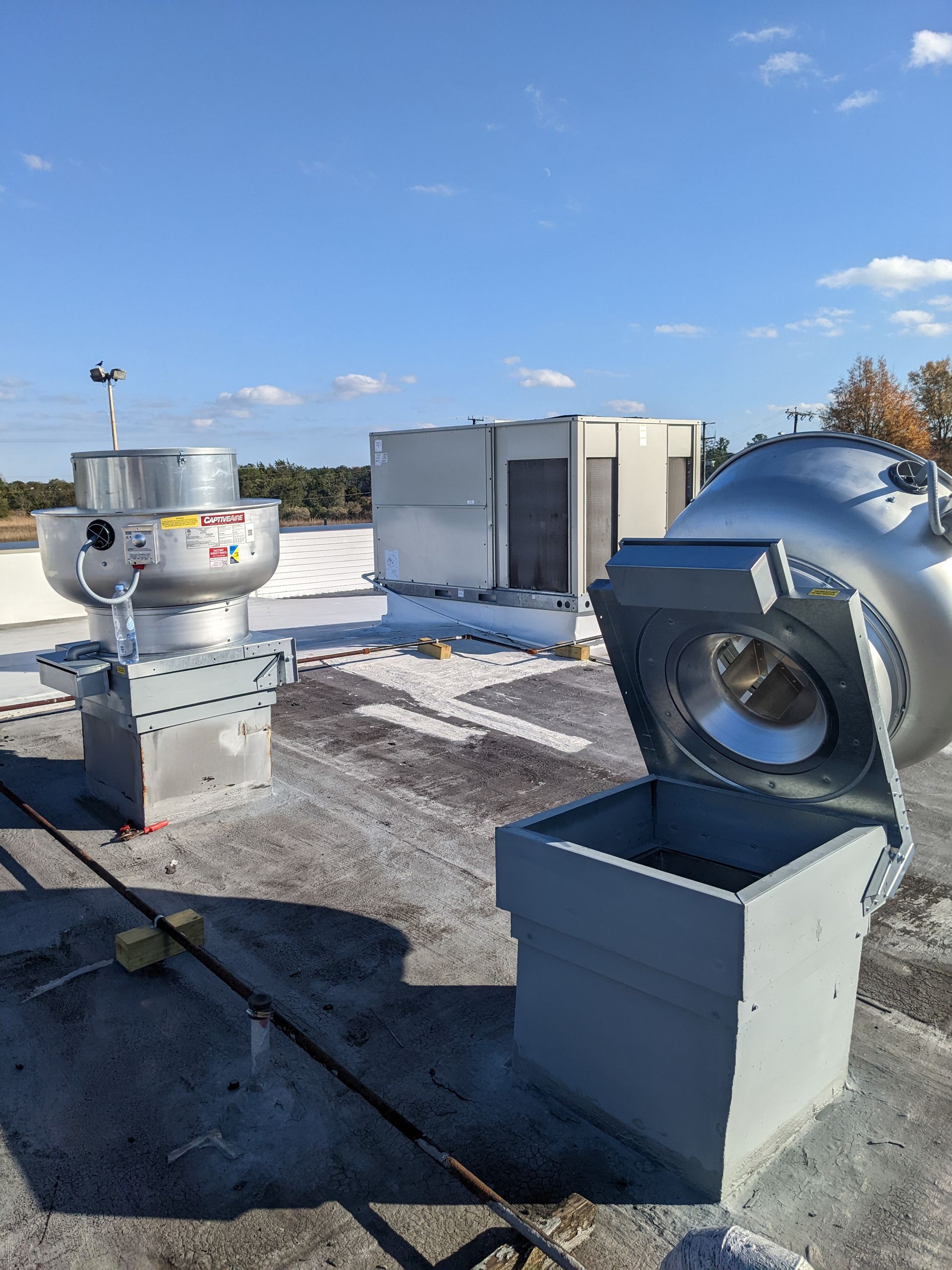 Rooftop with ventilation systems, silver vents against a blue sky.