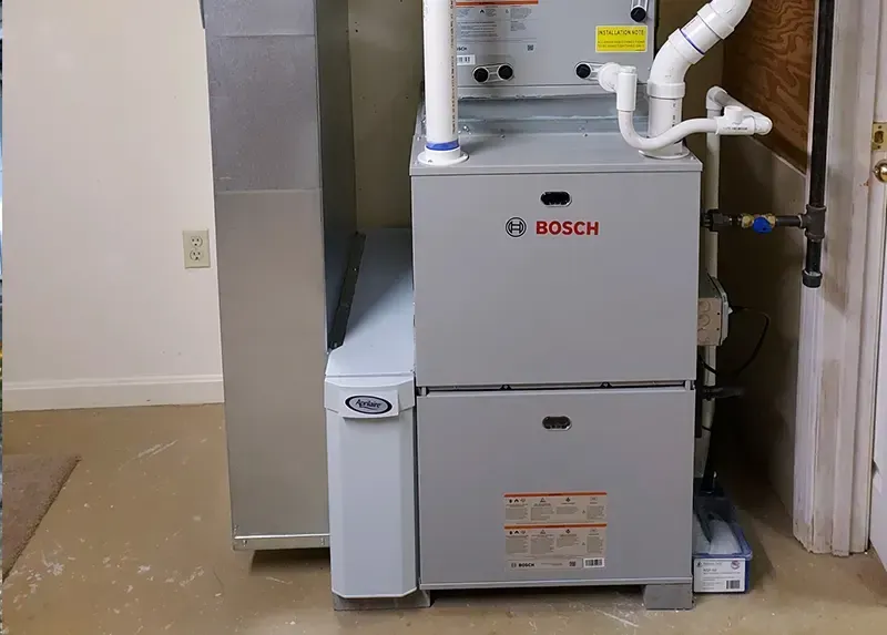 Bosch furnace and water softener in a utility room with ductwork and plumbing.