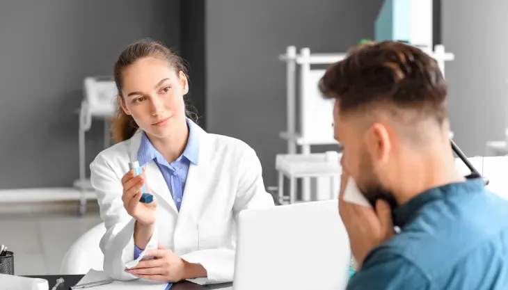 A doctor is talking to a patient who is blowing his nose.