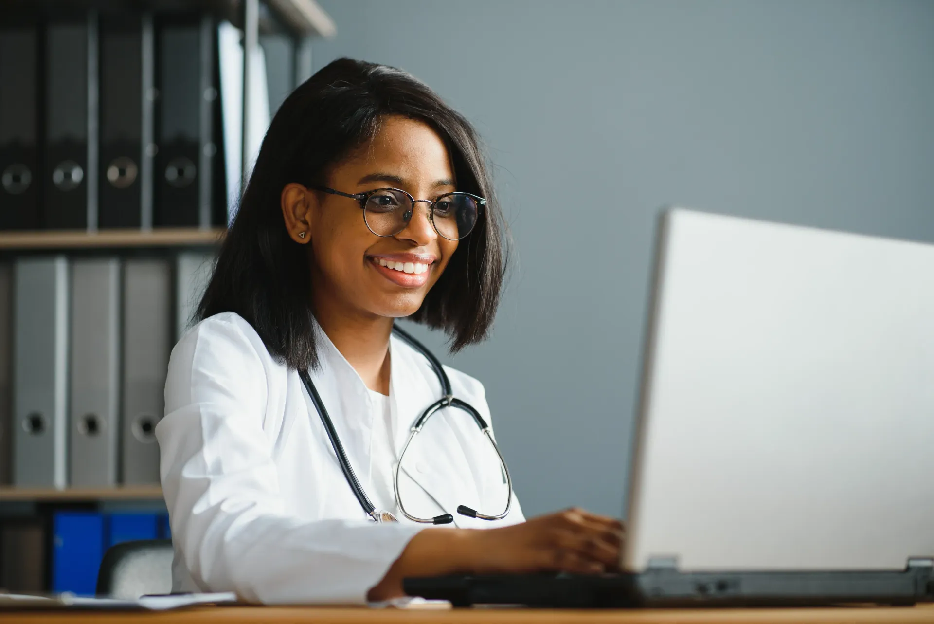 A nurse wearing a headset is sitting in front of a computer.