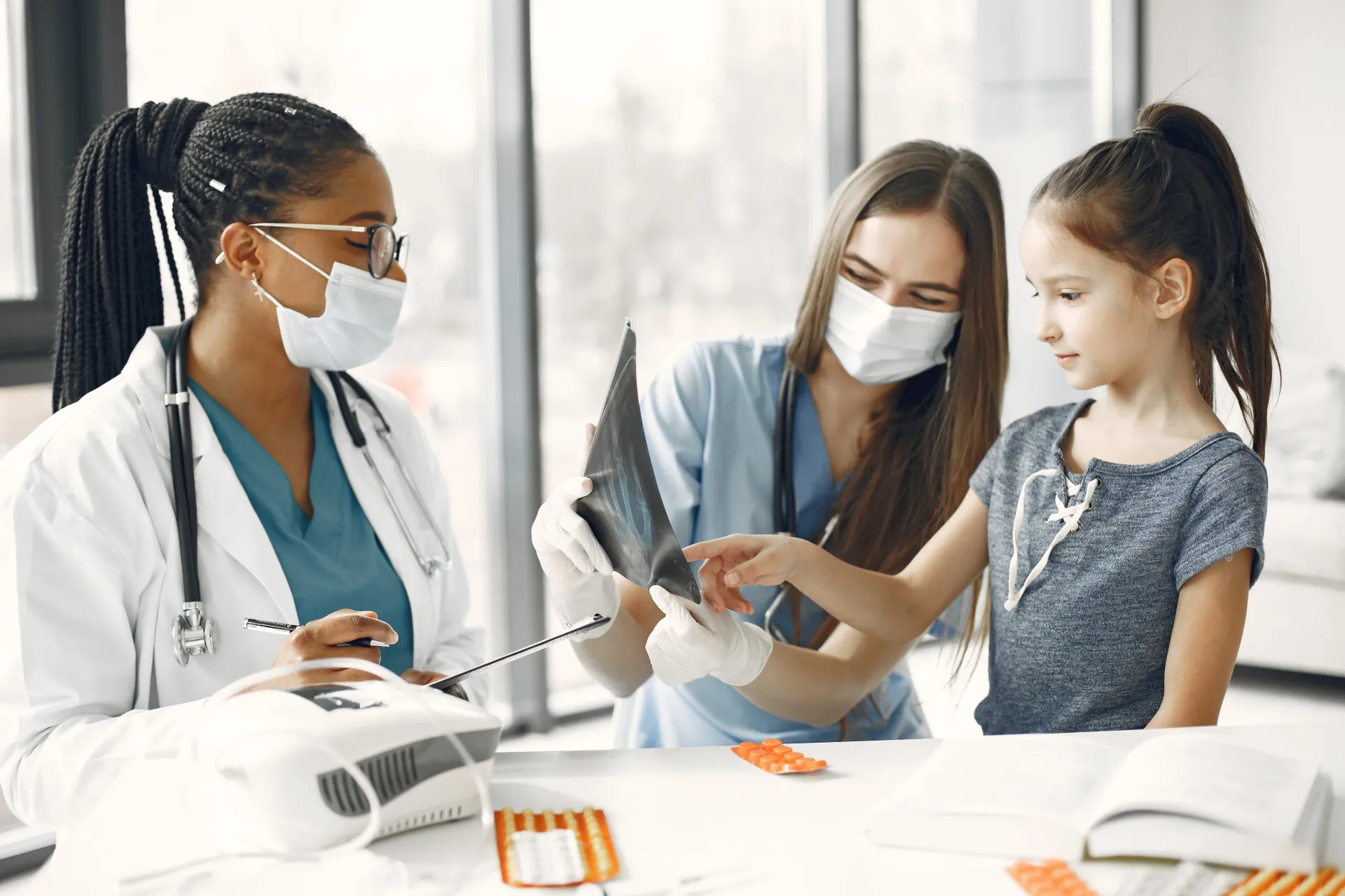 A doctor and nurse are talking to a little girl in a hospital.