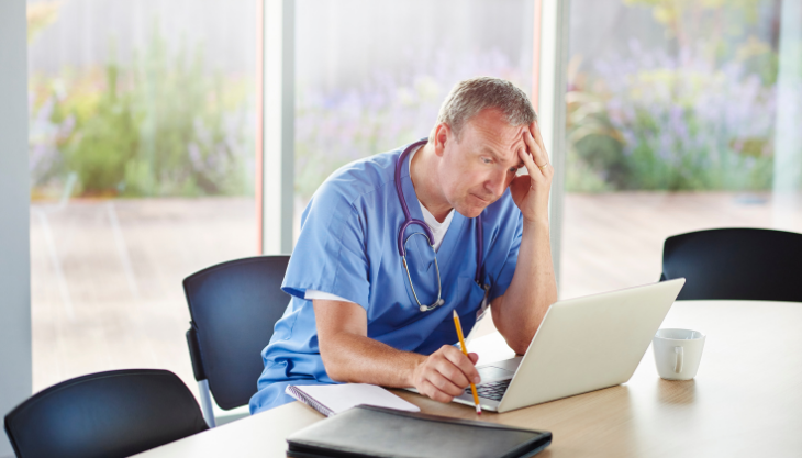 A zombie is sitting at a desk in front of a computer.