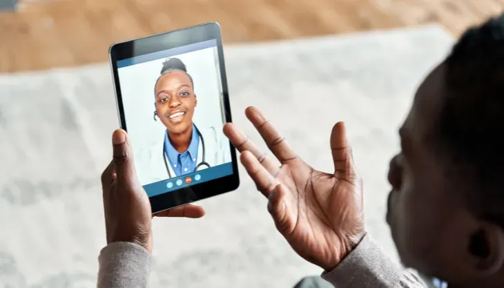 A doctor is using a laptop computer with a futuristic screen.