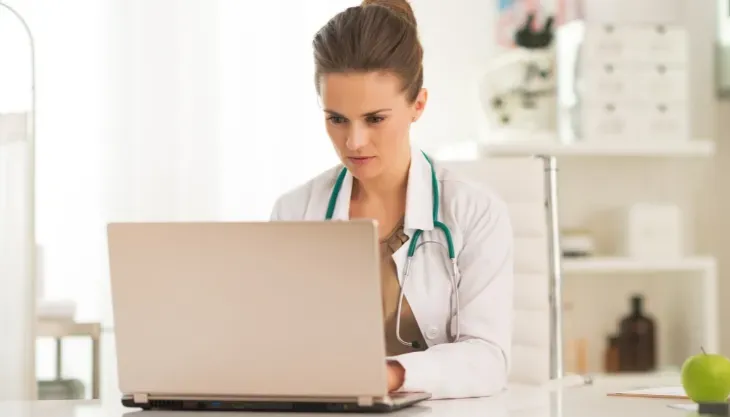 A doctor is using a laptop computer with a futuristic screen.