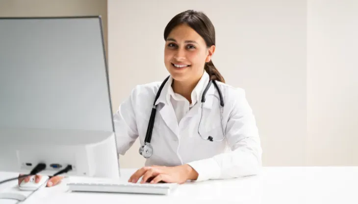A doctor is using a laptop computer with a futuristic screen.