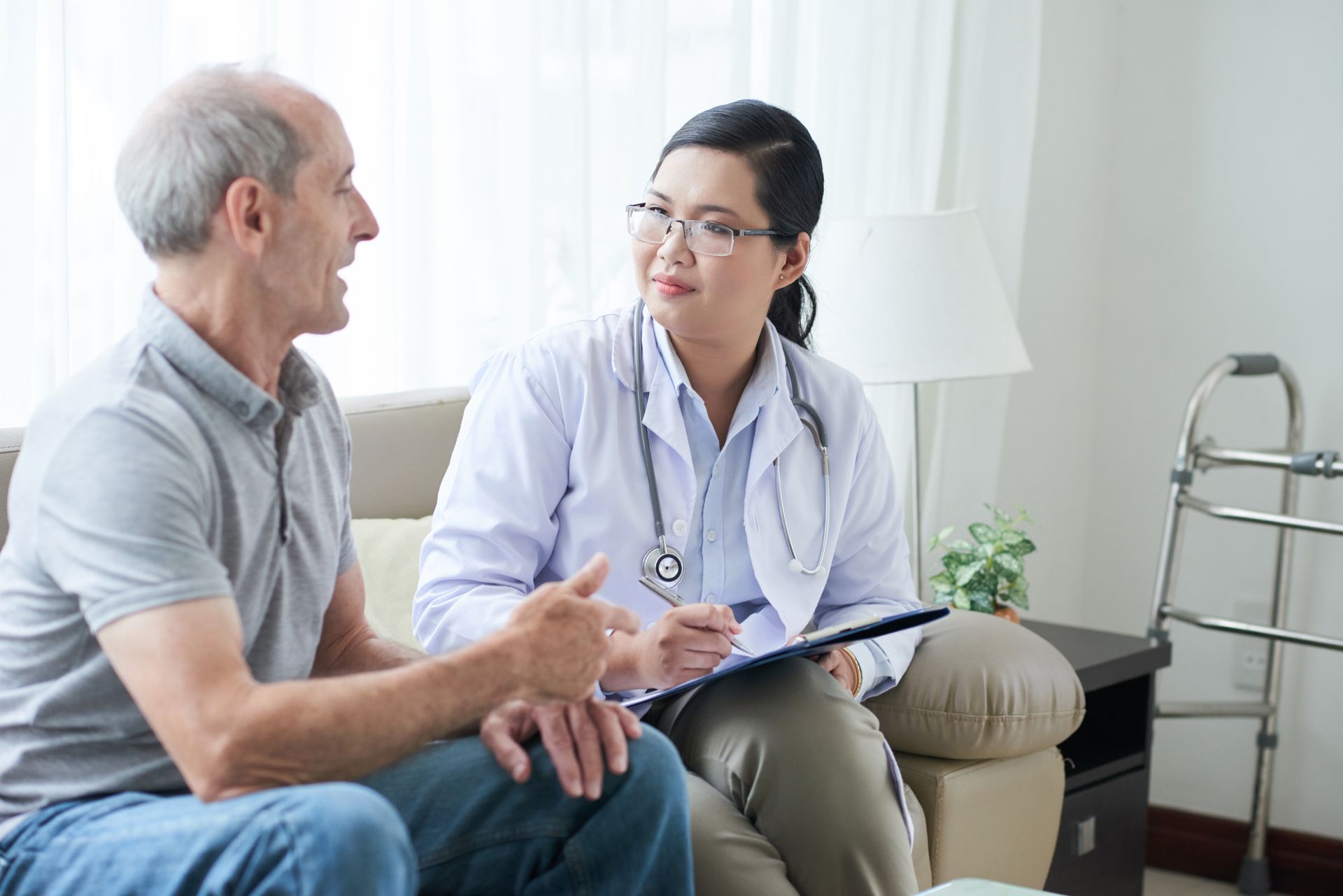 A doctor is talking to an elderly man on a couch.