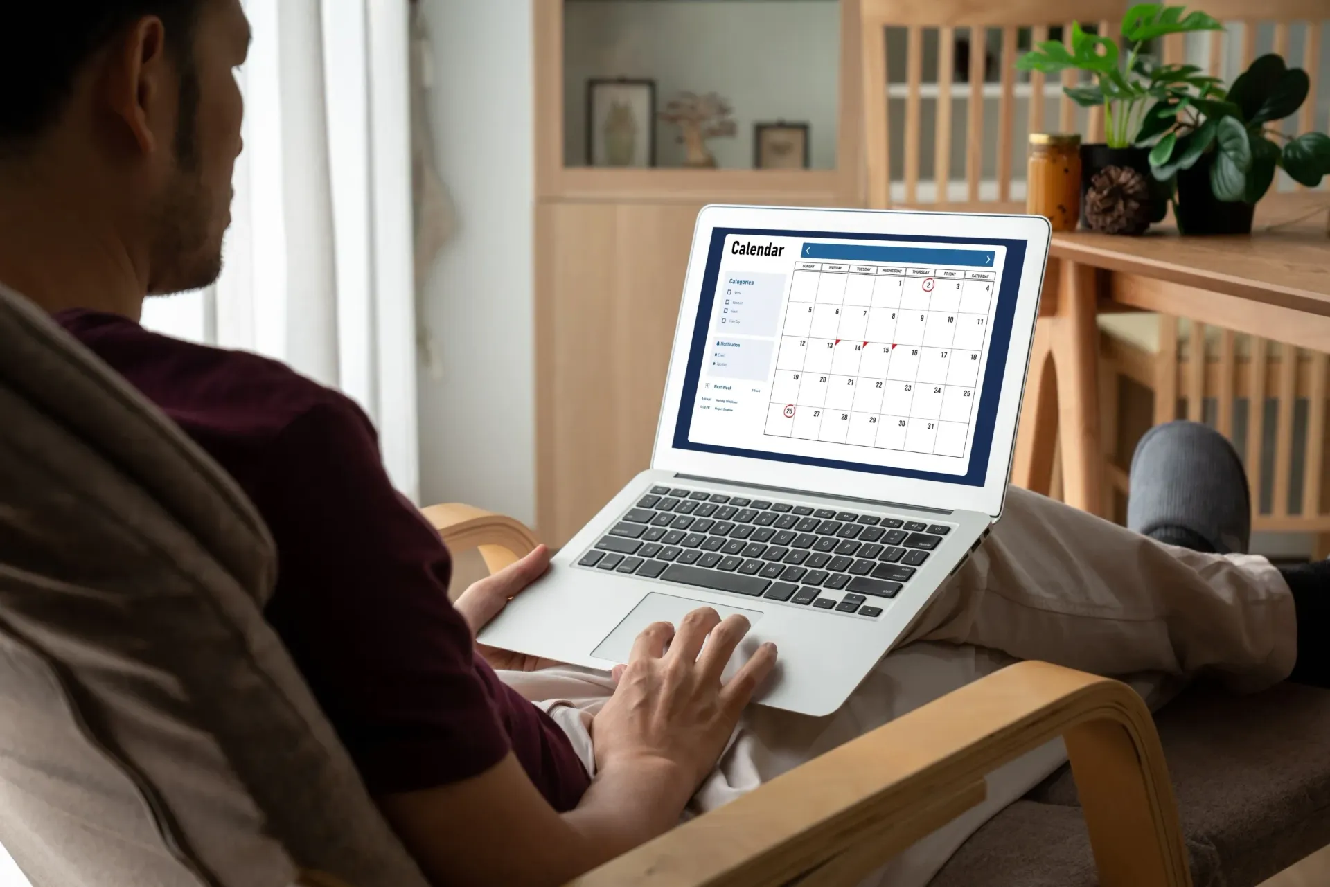 A man is sitting in a chair using a laptop computer.