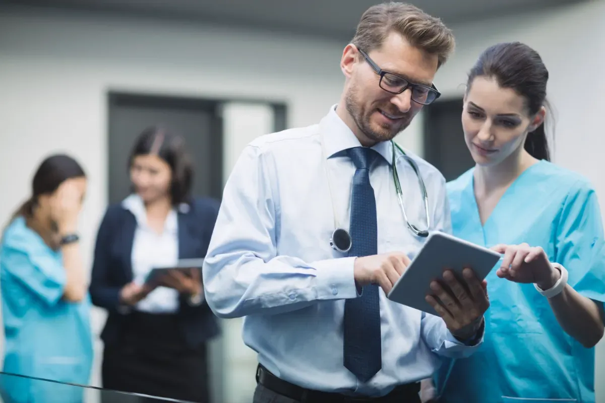 A doctor and a nurse are looking at a tablet in a hospital.