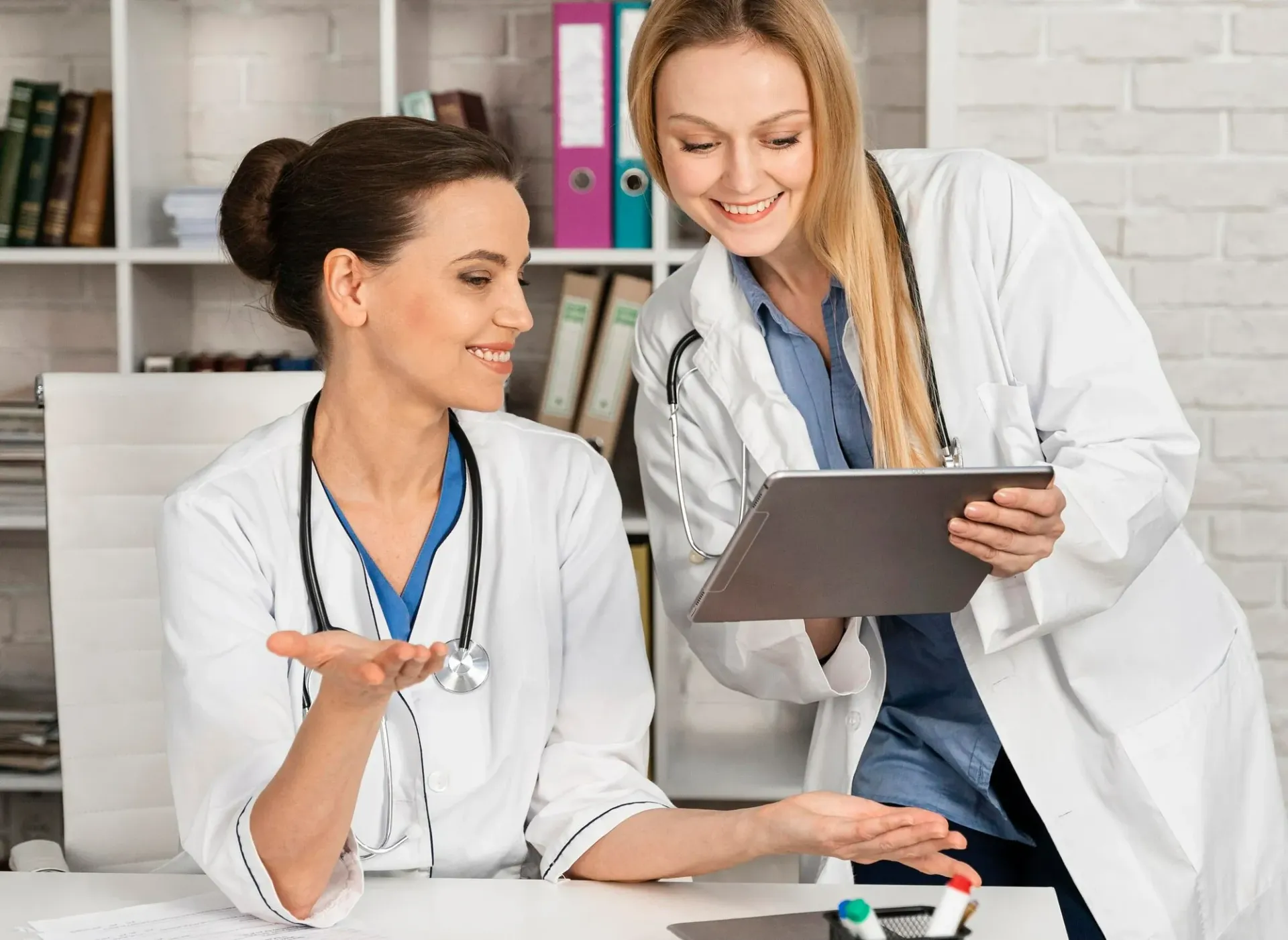 A doctor is sitting at a desk in front of a computer.