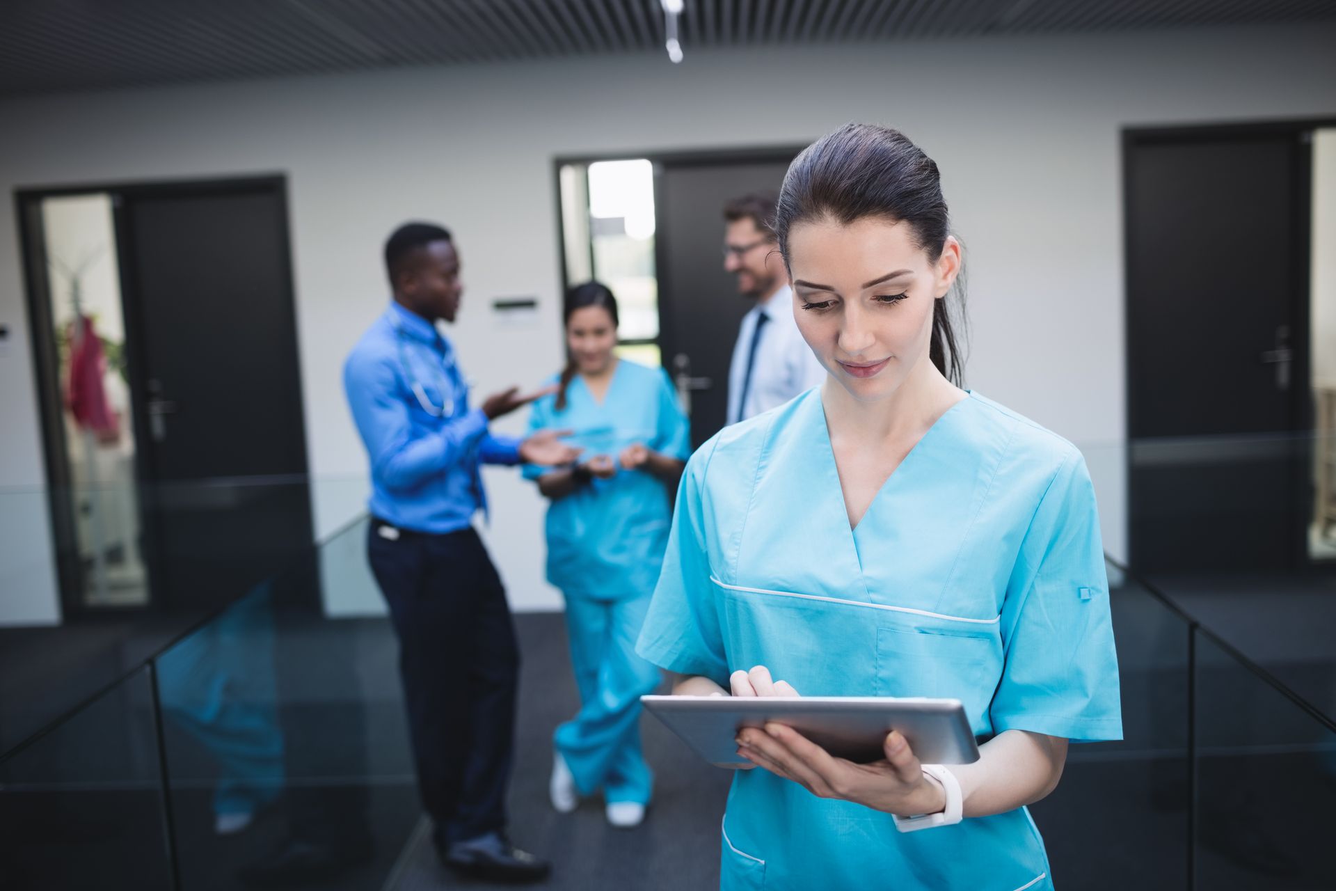 A healthcare staff member reviews real-time FHIR data on a tablet while her colleagues discuss patient care.