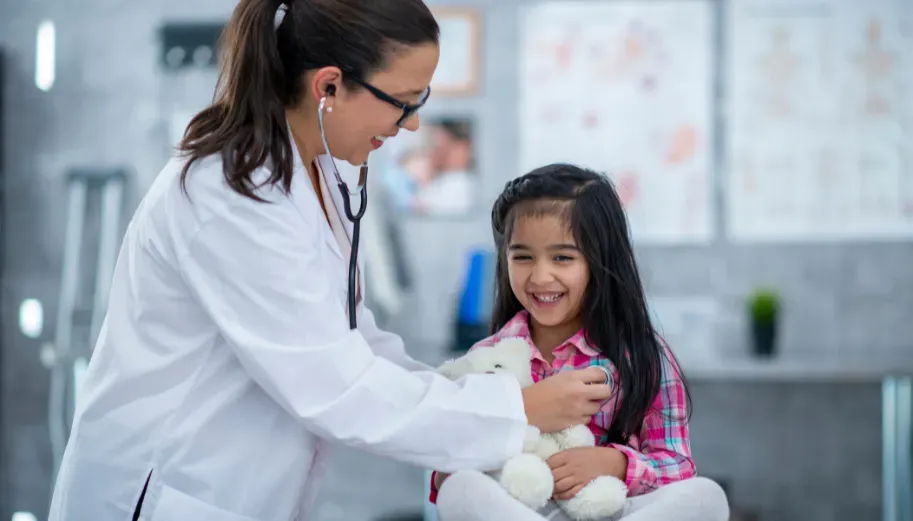 A doctor is listening to a little girl 's heart with a stethoscope.
