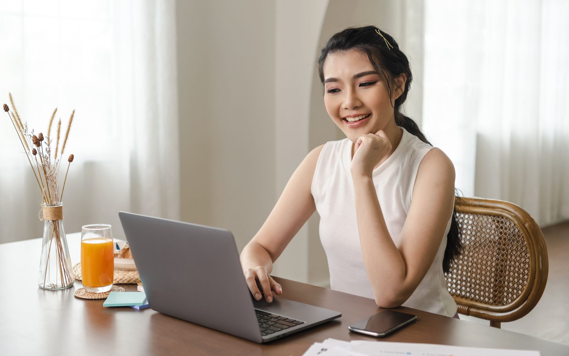 A woman is sitting at a table using a laptop computer.
