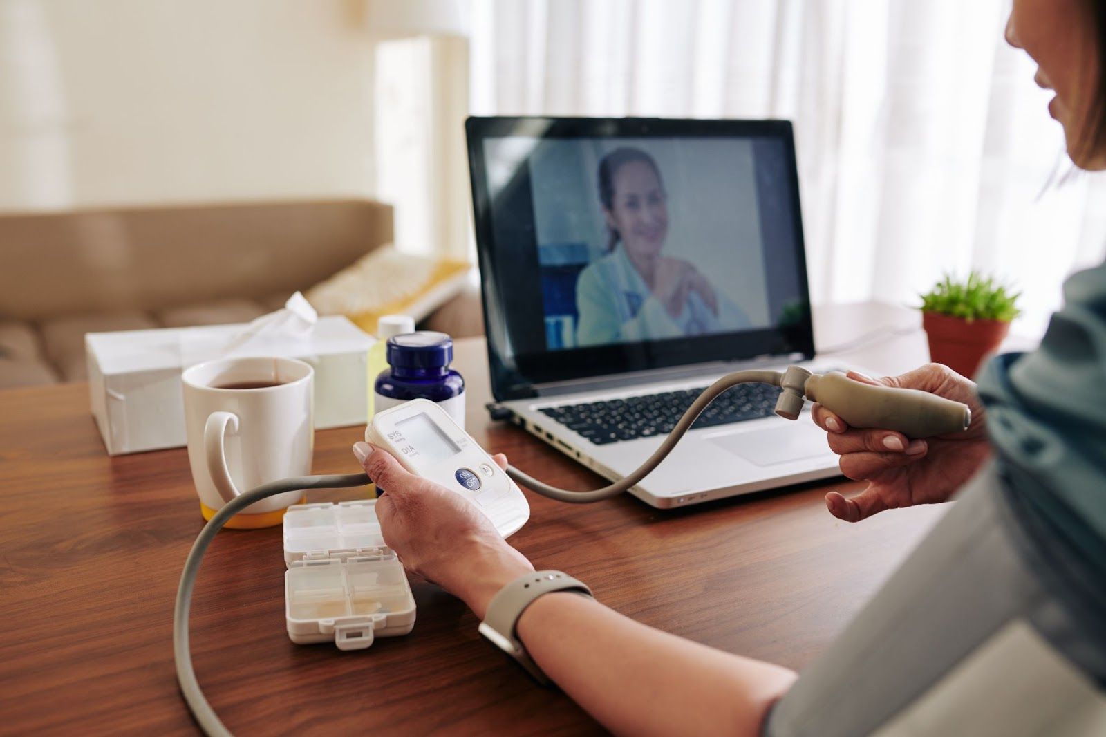To facilitate cardiology patient monitoring, a heart specialist holds a virtual consultation with her patient, instructing them to measure their blood pressure at home.