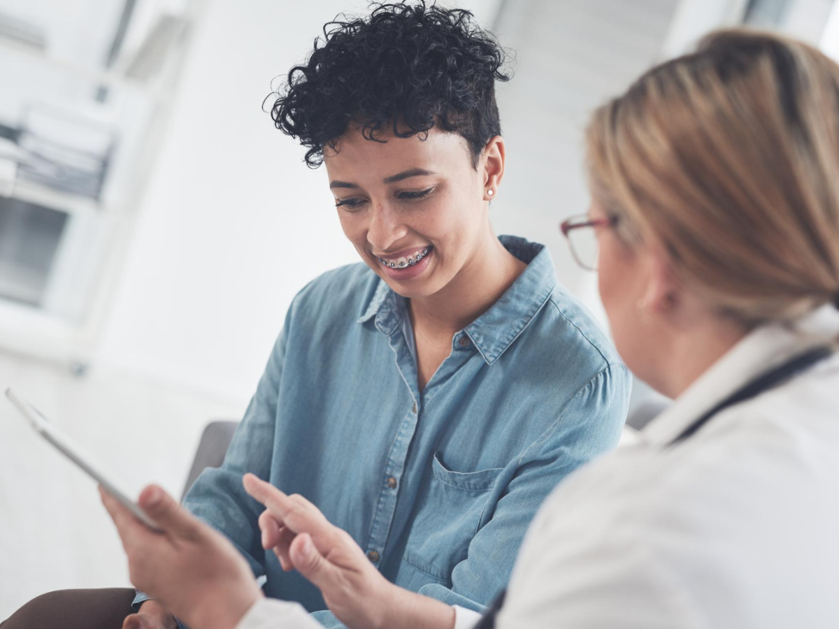 A patient checks in with a doctor, reviewing pre-filled forms on a tablet for faster intake.