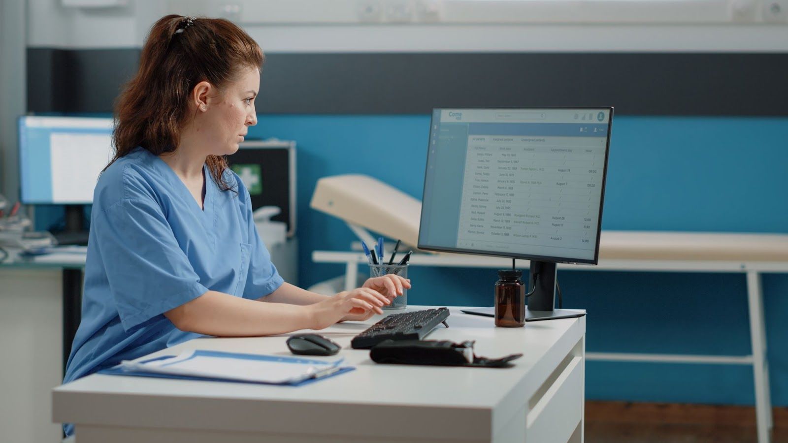 A nurse is sitting at a desk in front of a computer.