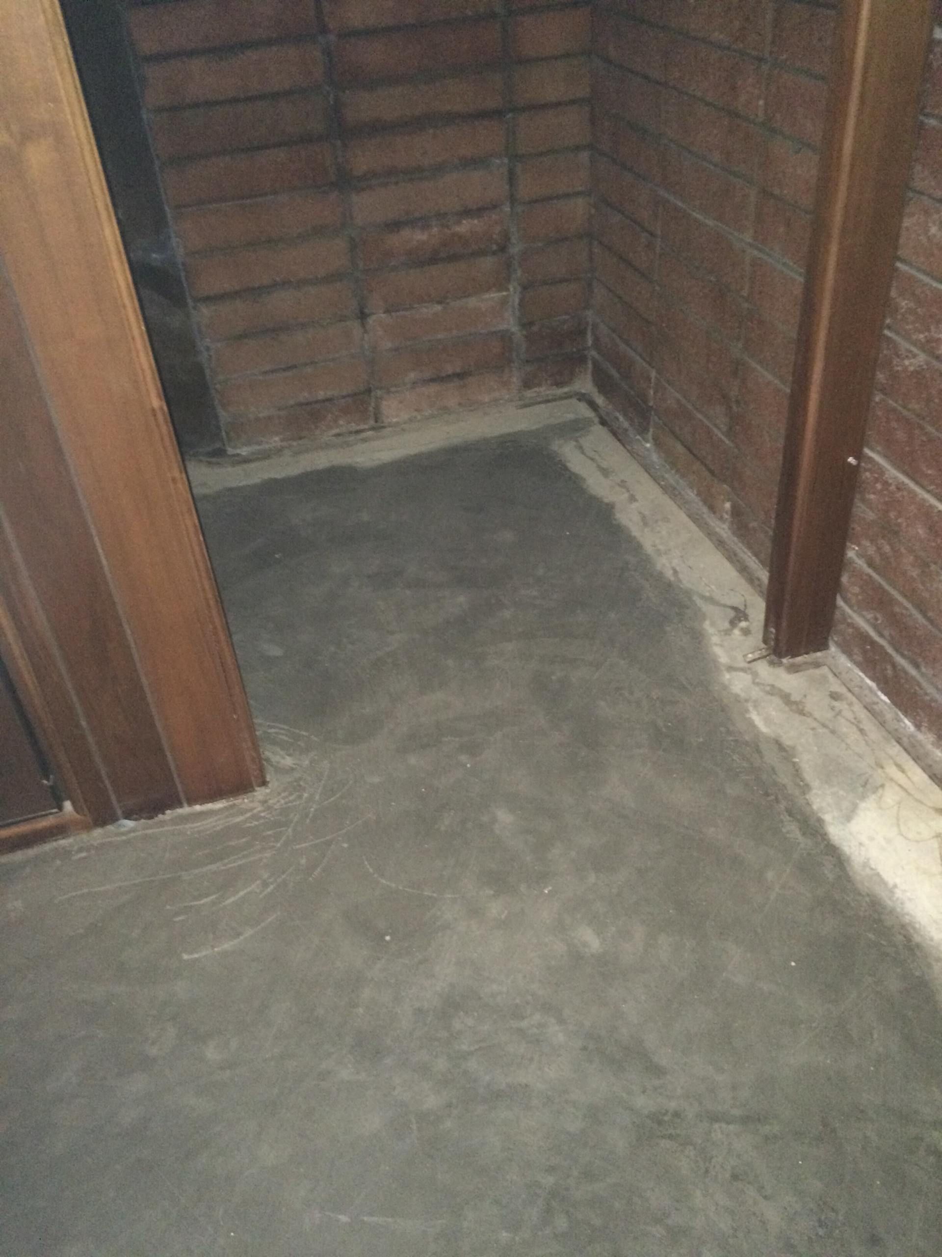 Cement floor in a dim room with wood walls, corner and beams.