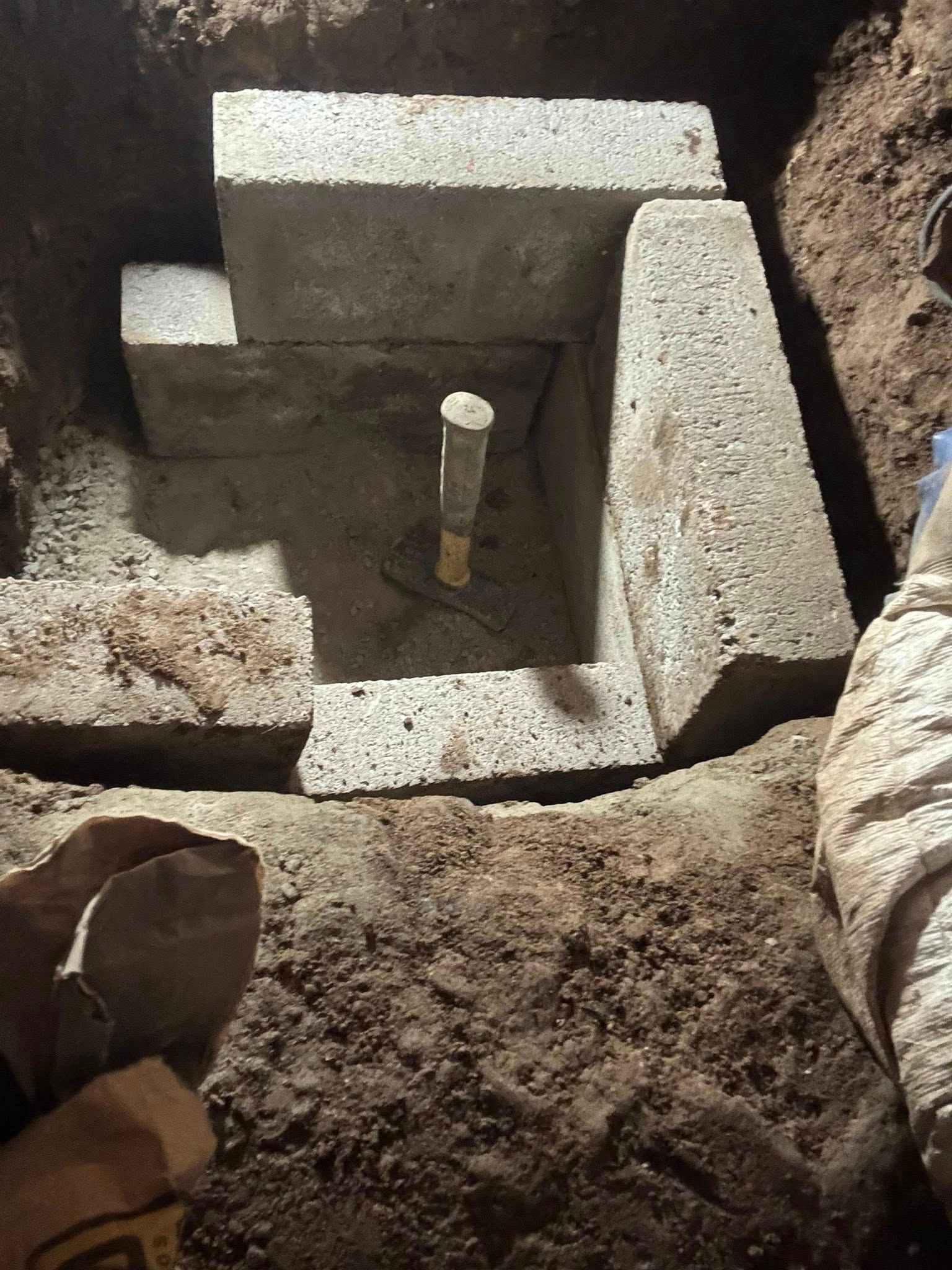 Concrete structure in a dug pit with a pipe protruding from the center.