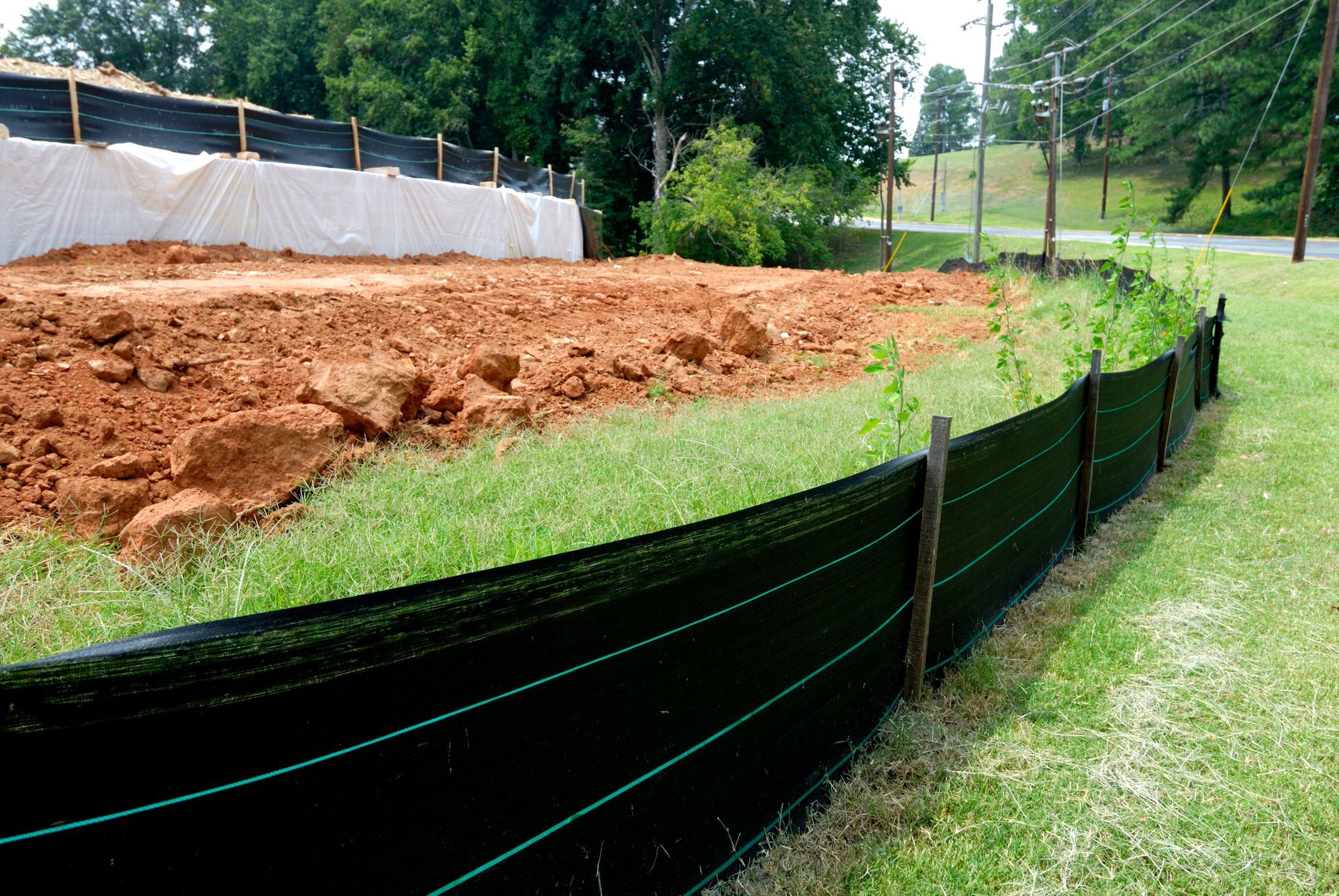 Person installing rebar grid on a dirt patio, next to a house. Green shirt, outside.