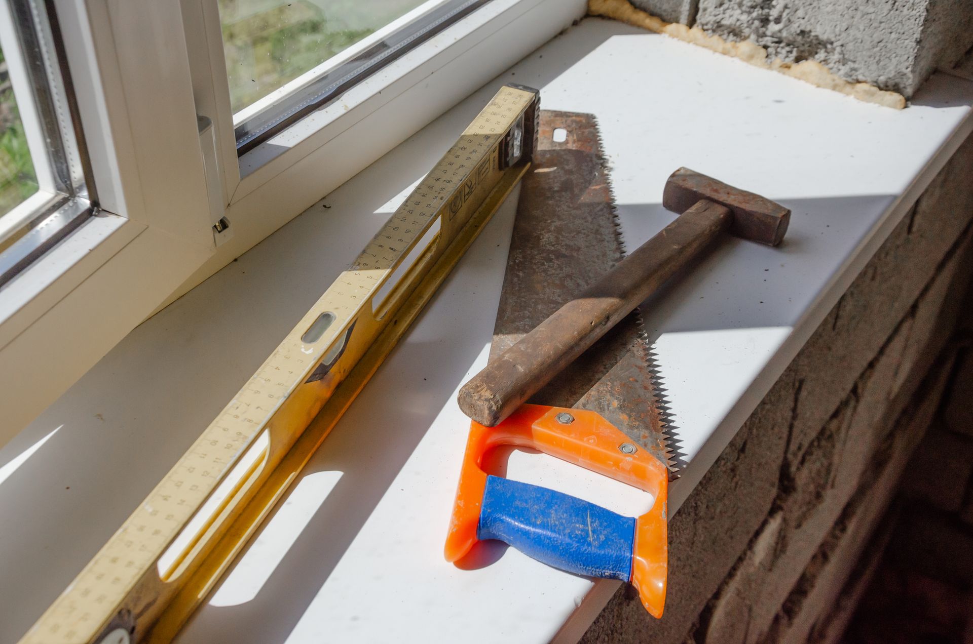 Man crawls into small brick opening, holding a flashlight and tools. Green grass surrounds the entrance.