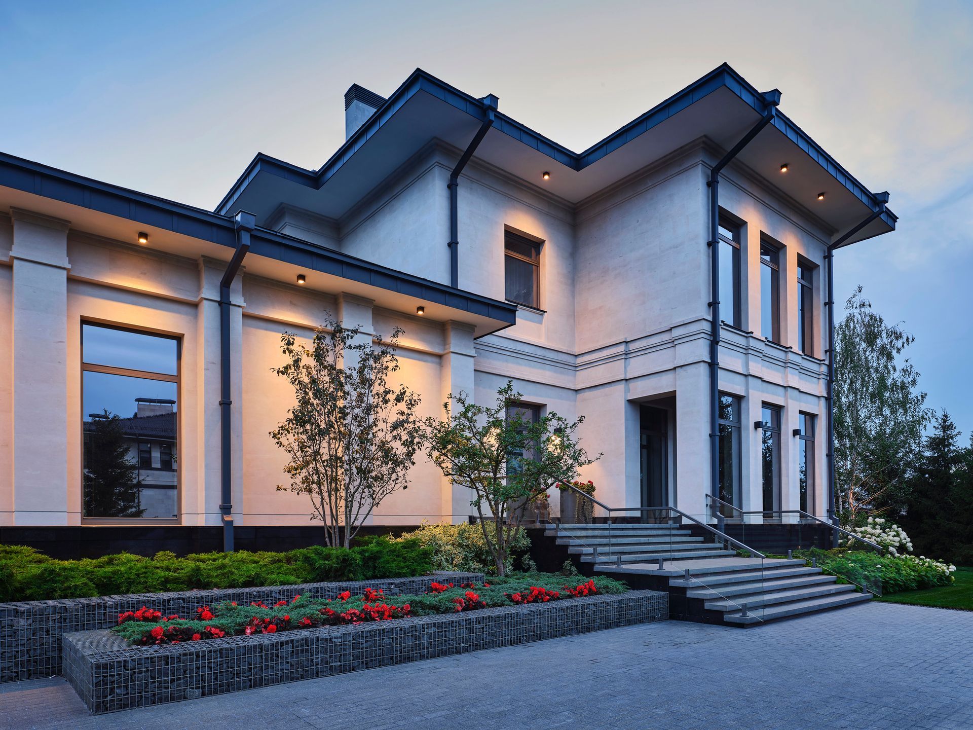 A wooden lakeside dock with tires hanging beneath a roofed structure, dirt foreground, and trees in the distance.