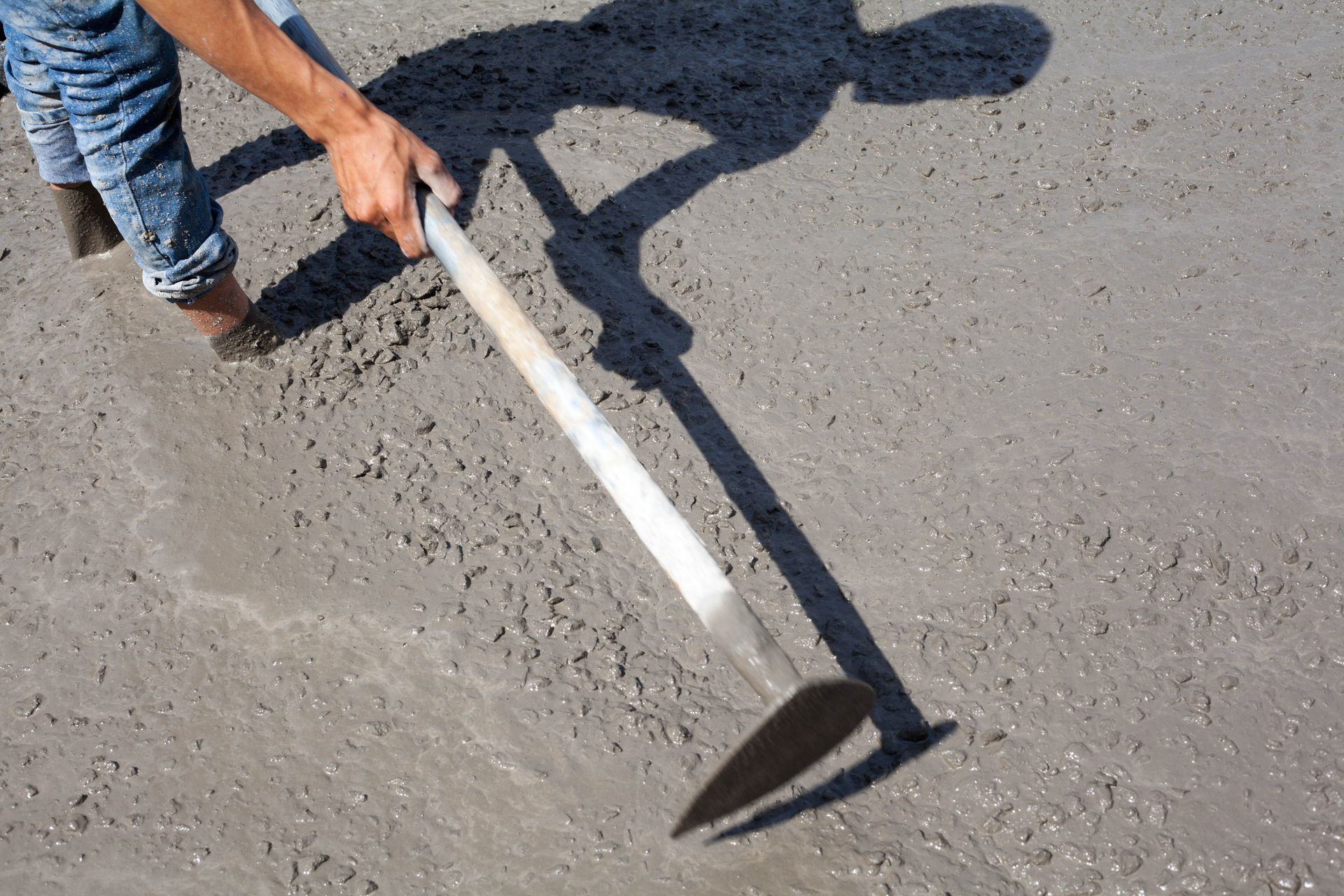 A person measures an old brick foundation in a dirt crawlspace with a tape measure.