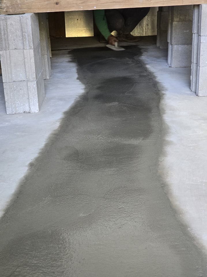 Person smoothing wet concrete between cinder block supports.