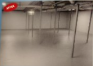 Empty, finished basement with support beams and a gray floor; the 