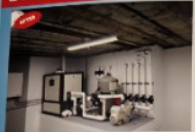 An updated basement with mechanical equipment, white pipes, and a fluorescent light. 