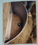 Metal corrugated well against a wall; person's legs visible in the background.