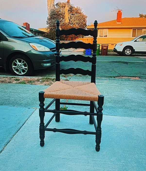 A black chair is sitting on the sidewalk in front of a car
