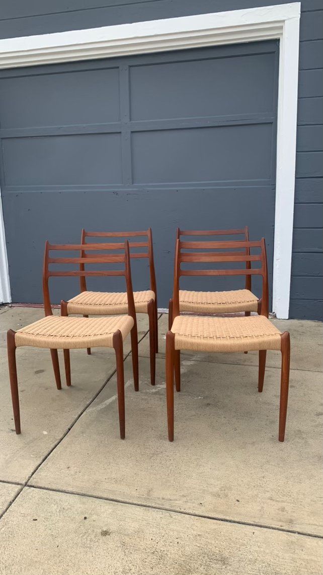 Four chairs are sitting on a sidewalk in front of a garage door.
