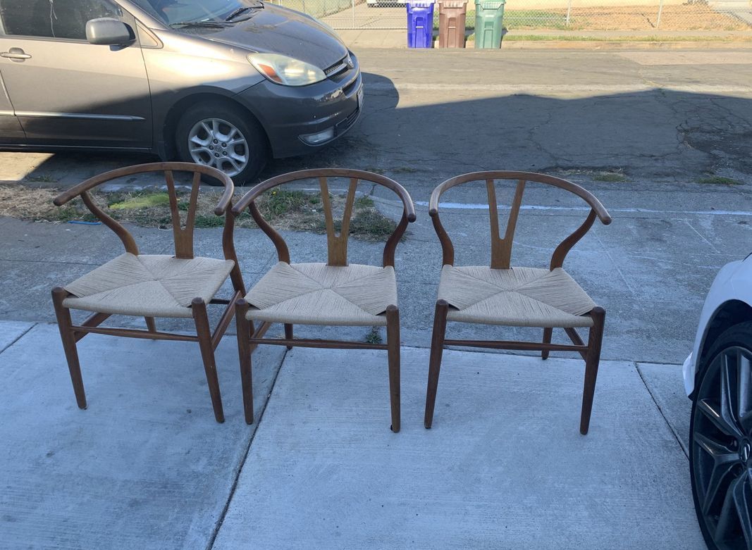 Three chairs are sitting on a sidewalk next to a car.