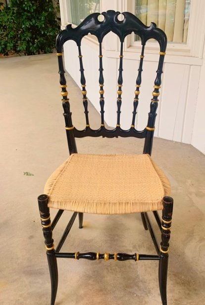 A black chair with a wicker seat sits on a porch