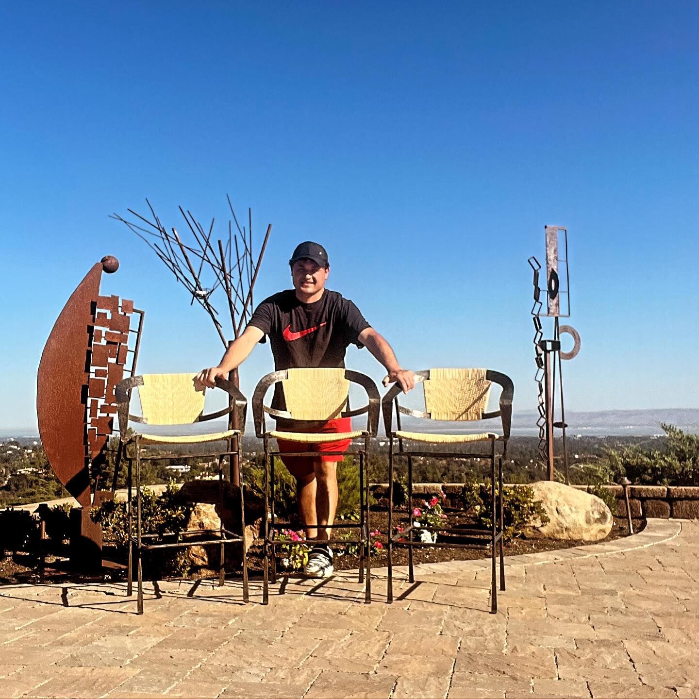 A man in a nike shirt stands between two chairs