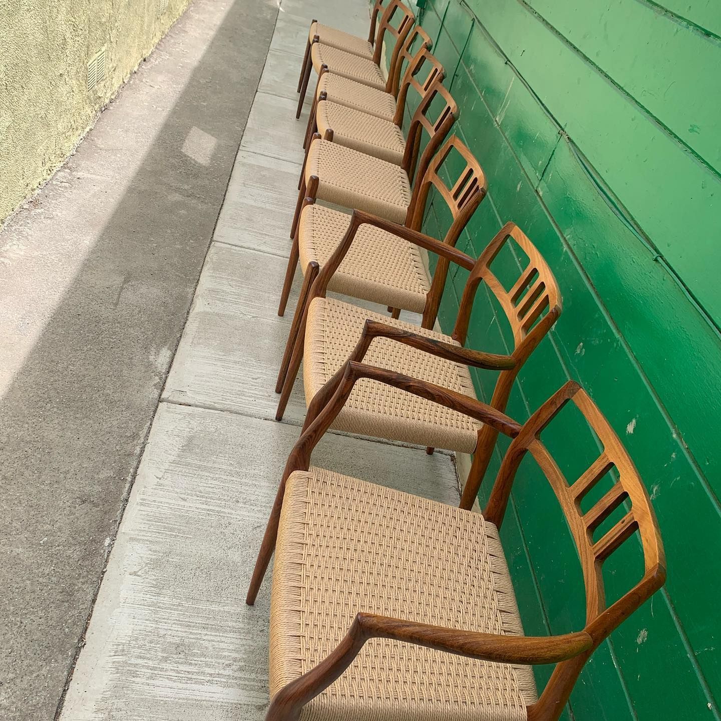 A row of chairs are lined up against a green wall