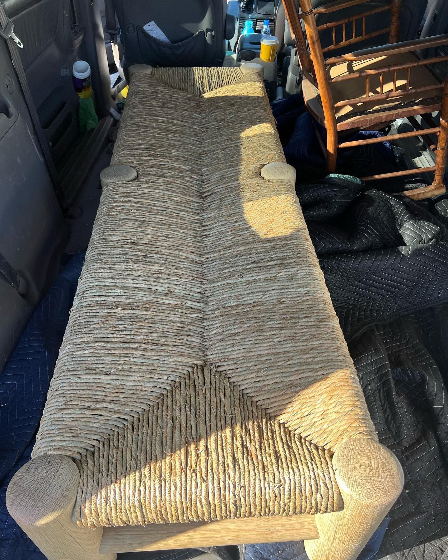 A wicker bench is sitting in the back of a car