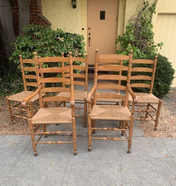 Four wooden chairs are lined up in front of a house