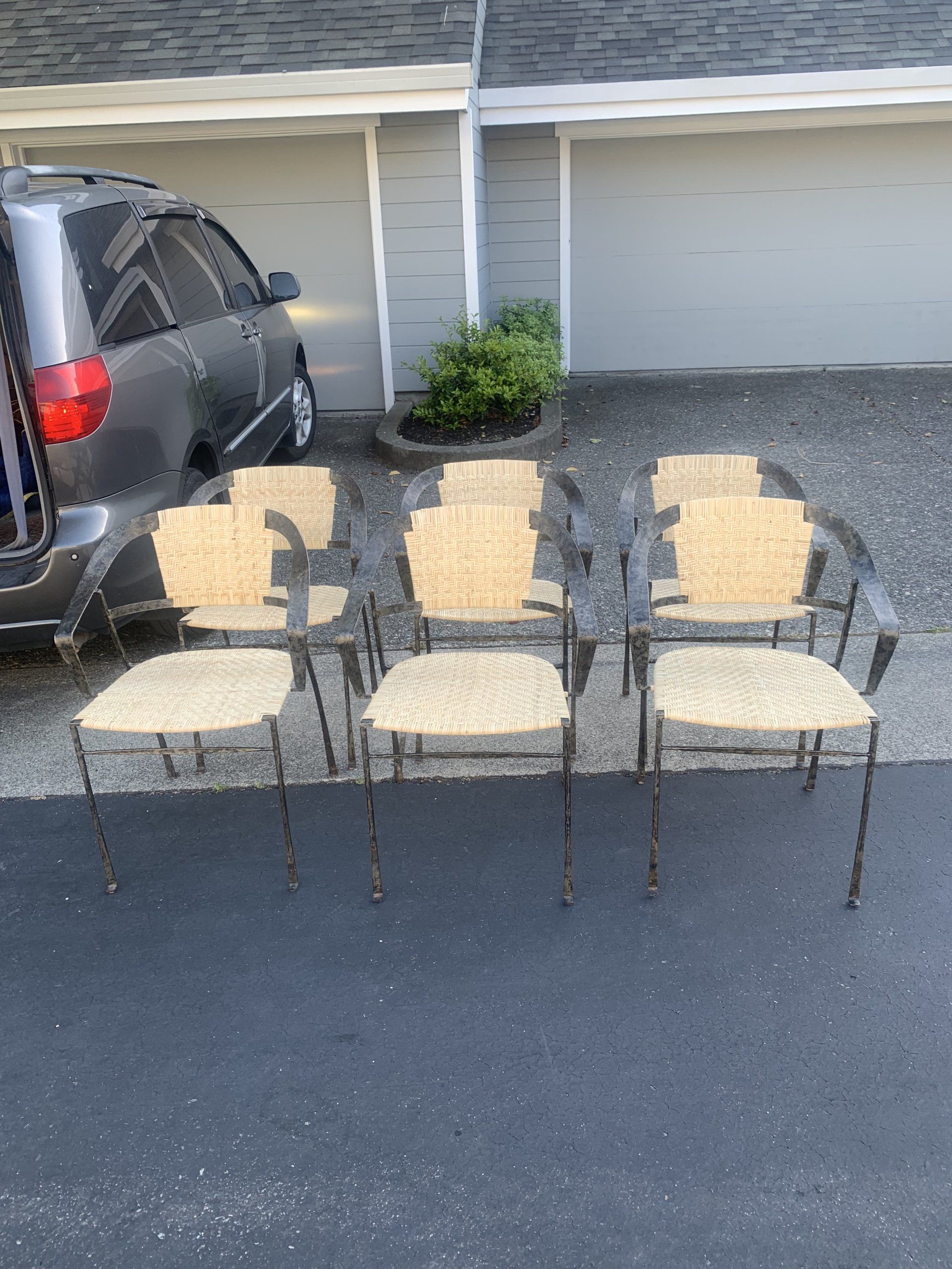 A row of chairs are sitting in a driveway next to a car.