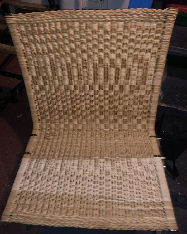 A wicker chair is wrapped in plastic and sitting on a table