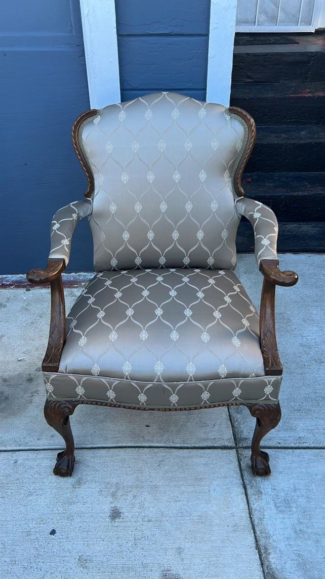 A chair is sitting on a sidewalk in front of a garage door.