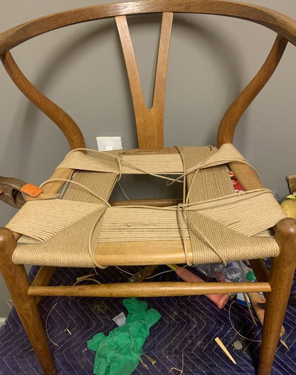 A wooden chair with a wicker seat is being repaired.