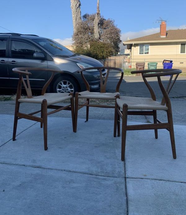 Three chairs are sitting on a sidewalk in front of a car