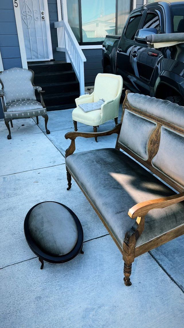 A row of chairs and a bench are sitting on a sidewalk in front of a house.