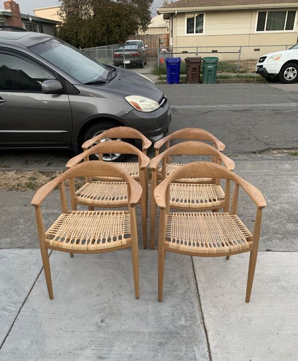 Four chairs are sitting on a sidewalk in front of a car.